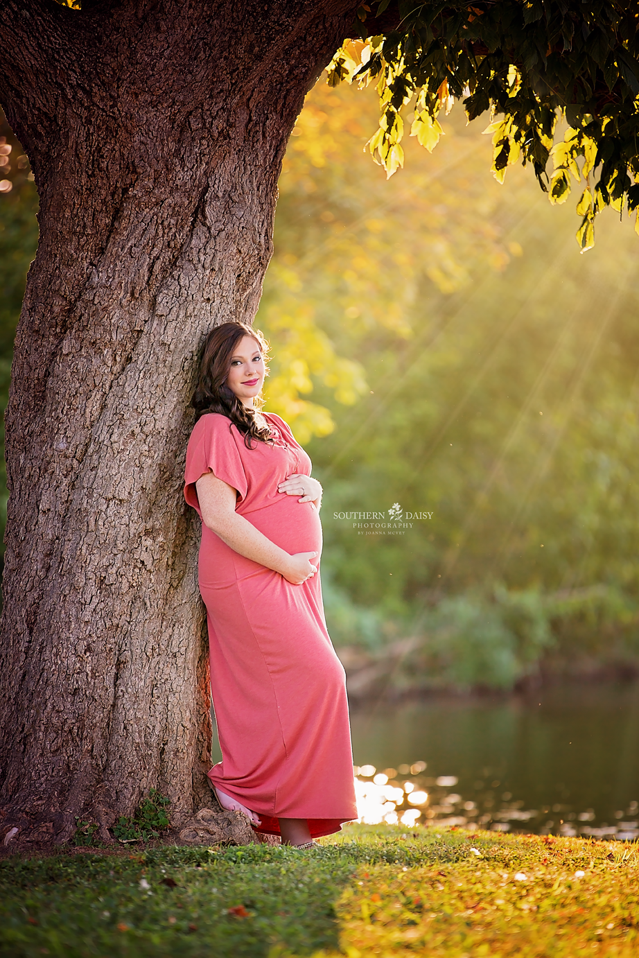 magical light shining on expectant mother leaning against tree near creek - nashville maternity photographer
