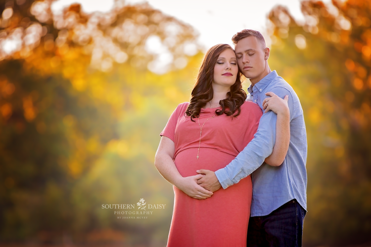 Expectant couple embracing in front of autumn leaves - Nashville maternity photographer