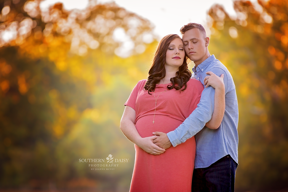 Expectant couple embracing in front of autumn leaves - Nashville maternity photographer