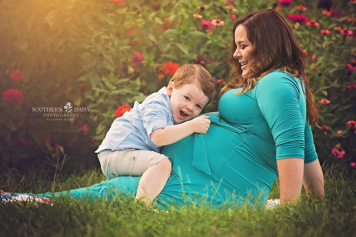 toddler boy sitting on pregnant mom's lap and hugging belly - nashville maternity photographer